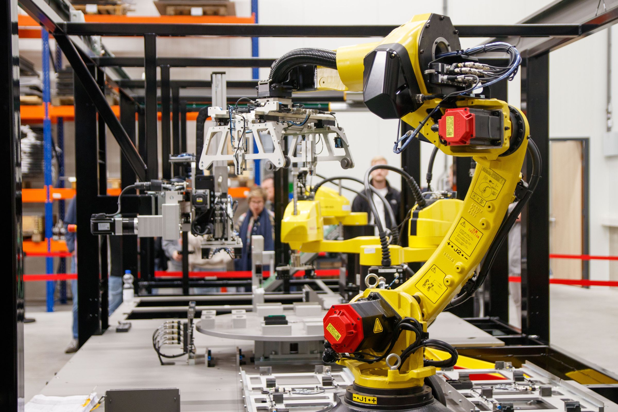 Yellow industrial robot working inside a guarded automation cell